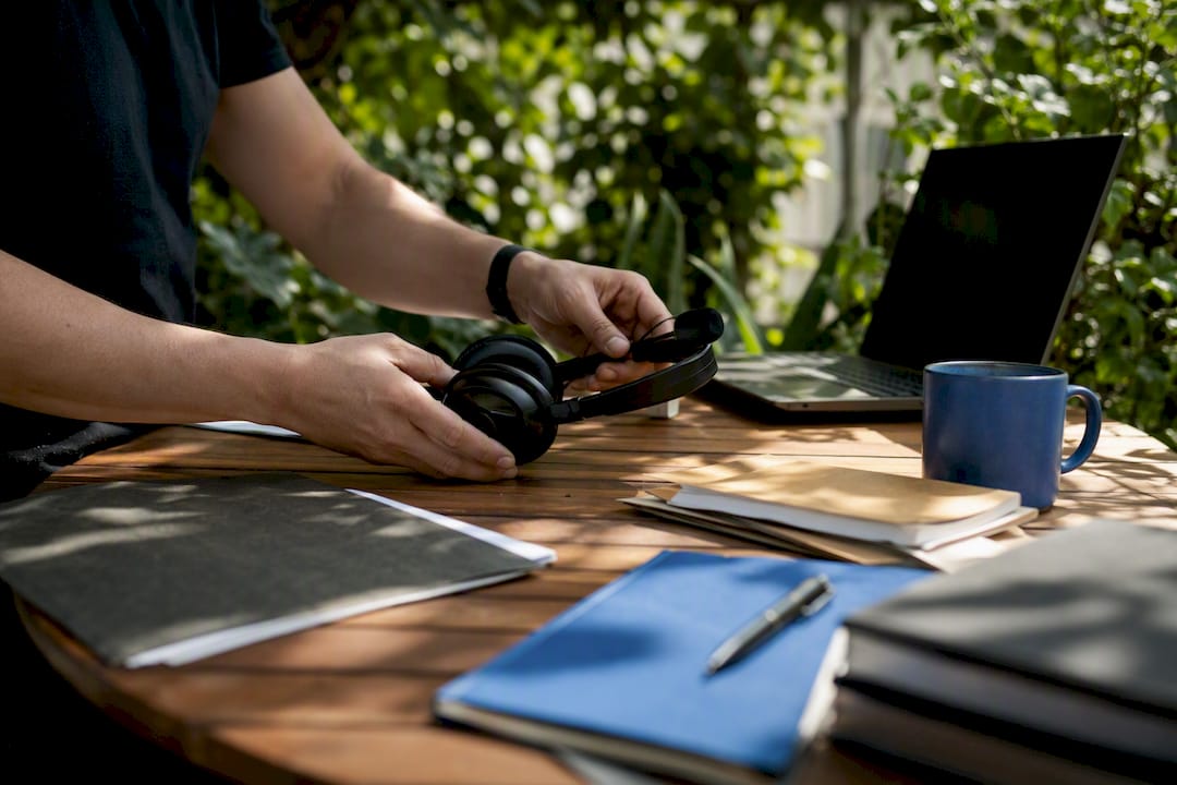 Hands adjusting headset near dark workstation
