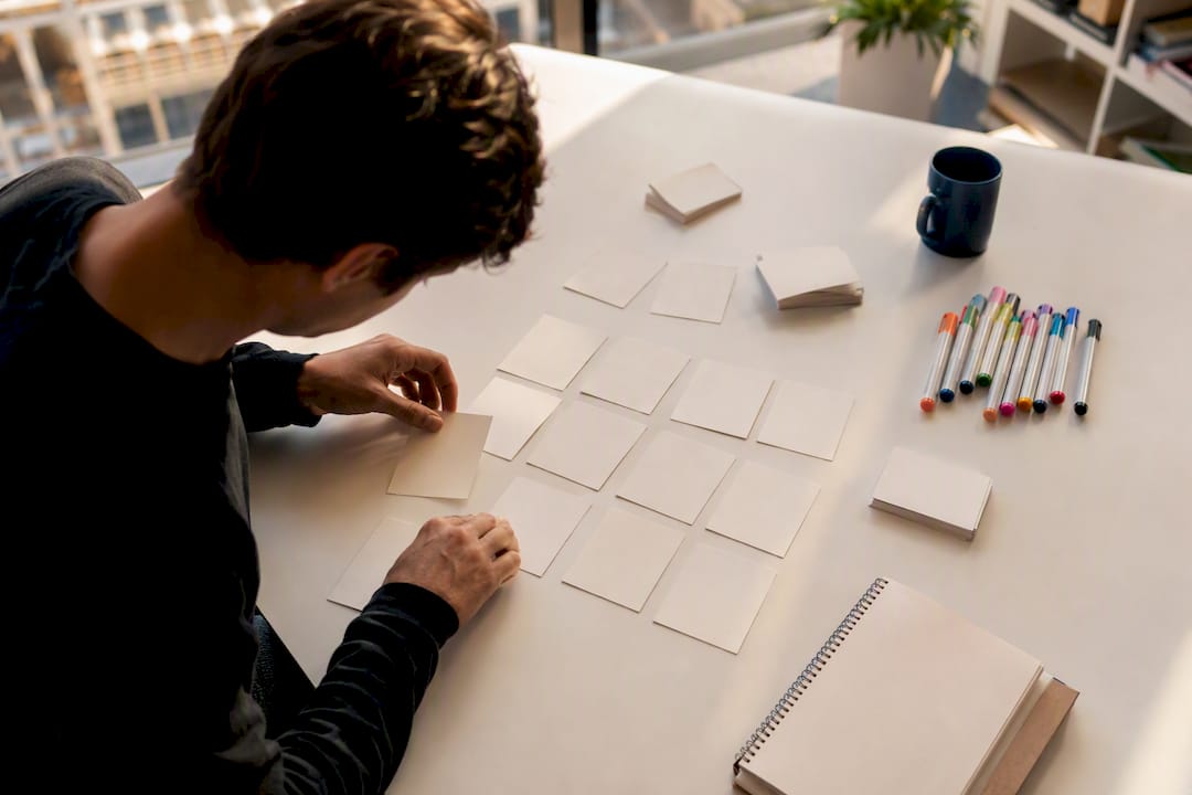 Hands arranging blank user flow cards