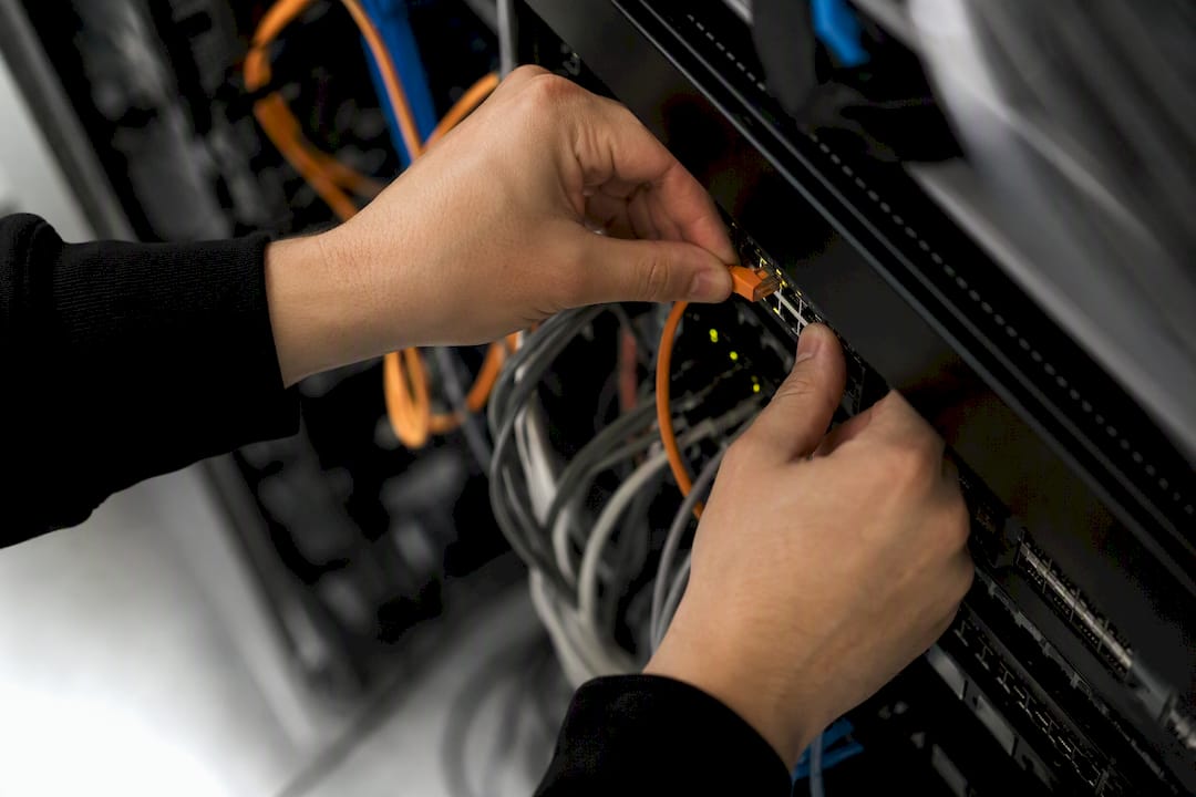 Technician connecting network cable in server rack