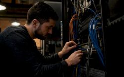 Hands connecting cables in a data center